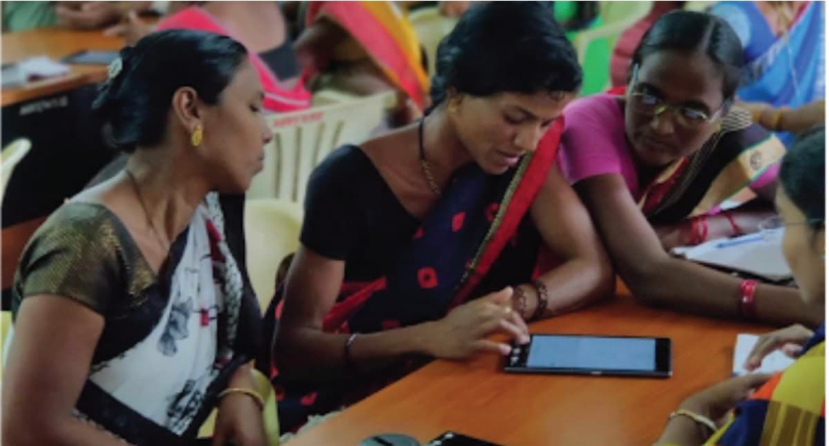 Community health workers gathered around a tablet, reviewing field data together